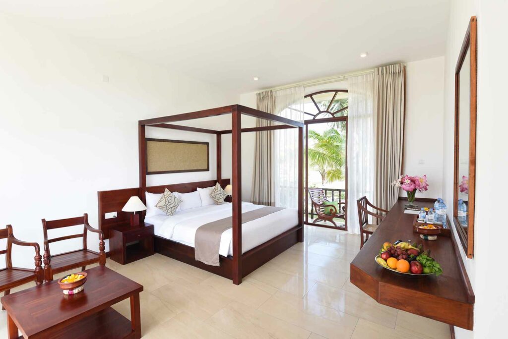 Foto eines Hotelzimmers mit Himmelbett und Aussicht auf eine Palme
